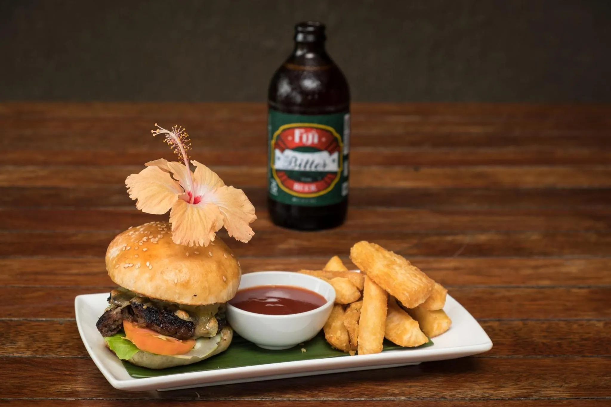Un hamburger, des frites et une bière sont présentés sur une table en bois.