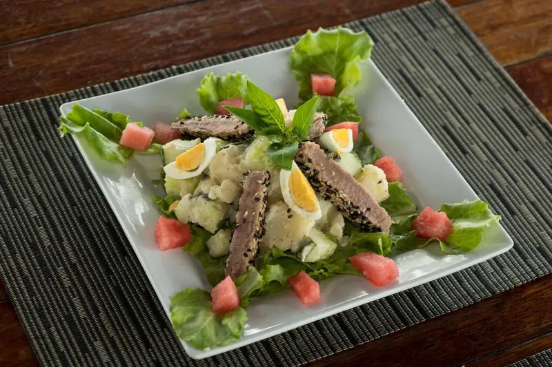 Assiette de salade composée avec des dés de pastèque, des œufs et du thon.