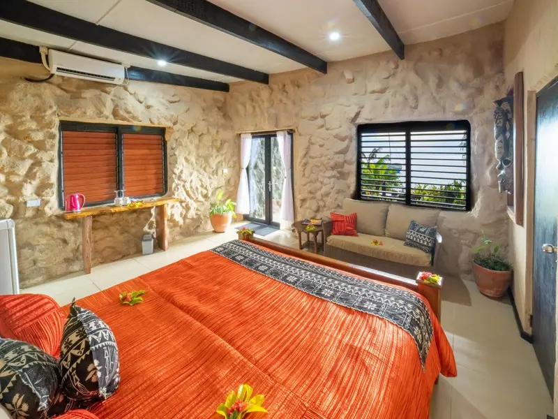Une chambre à coucher lumineuse avec un lit recouvert d'une couverture orange et un coin salon.