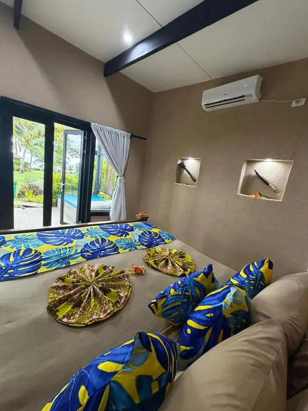 Une chambre décorée de motifs tropicaux offre une vue sur une piscine extérieure.