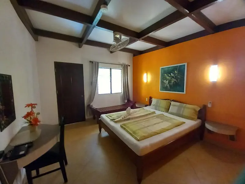 Une chambre lumineuse avec un lit fait et un bureau en bois.