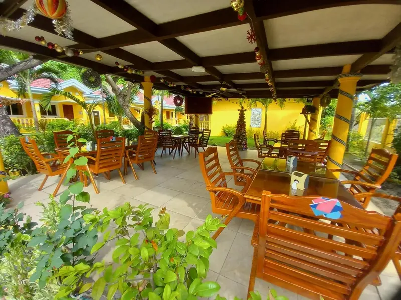 Terrasse ombragée avec tables et chaises en bois.