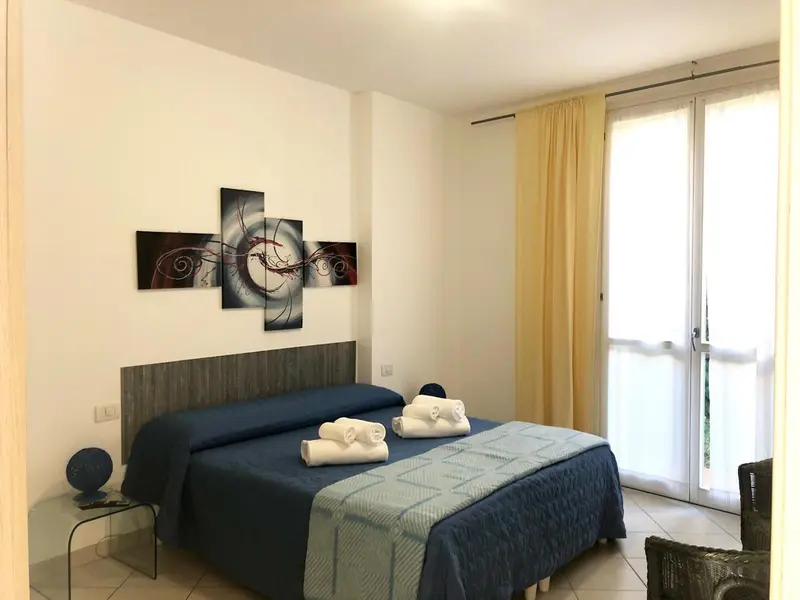 Une chambre lumineuse avec un grand lit et un tableau décoratif au mur.