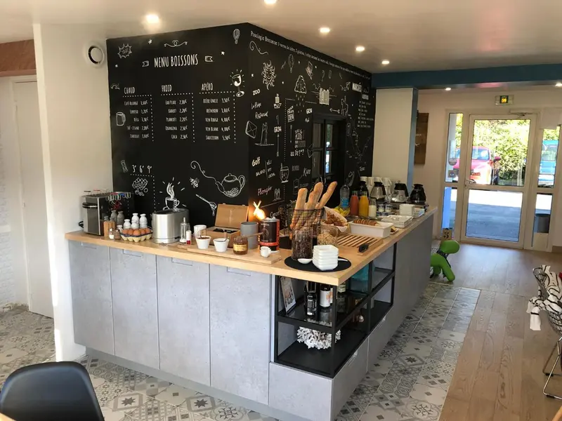 Un comptoir de boissons propose une variété de cafés, thés et pâtisseries dans un intérieur lumineux.