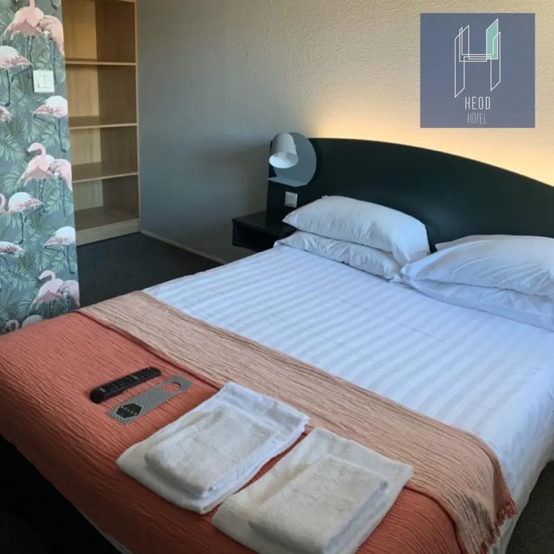 Une chambre d'hôtel avec un lit recouvert d'une couverture rose et de coussins blancs.