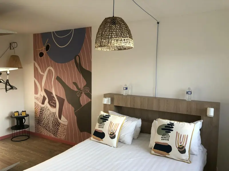 Une chambre lumineuse avec un lit double et une décoration murale abstraite.