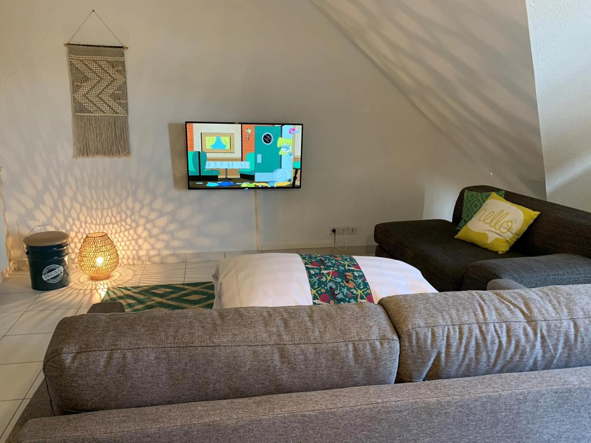 Espace de détente avec canapé, coussin et télévision.