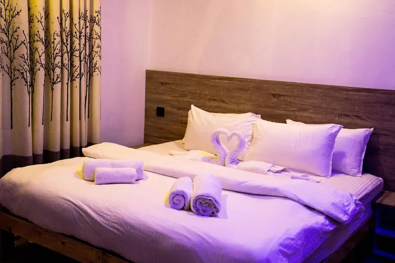 Lit préparé avec des serviettes en forme de cœur dans une chambre d'hôtel.