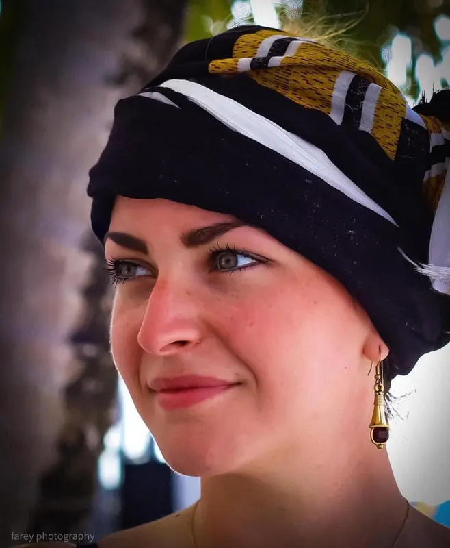 Portrait d'une femme souriante portant un foulard coloré.