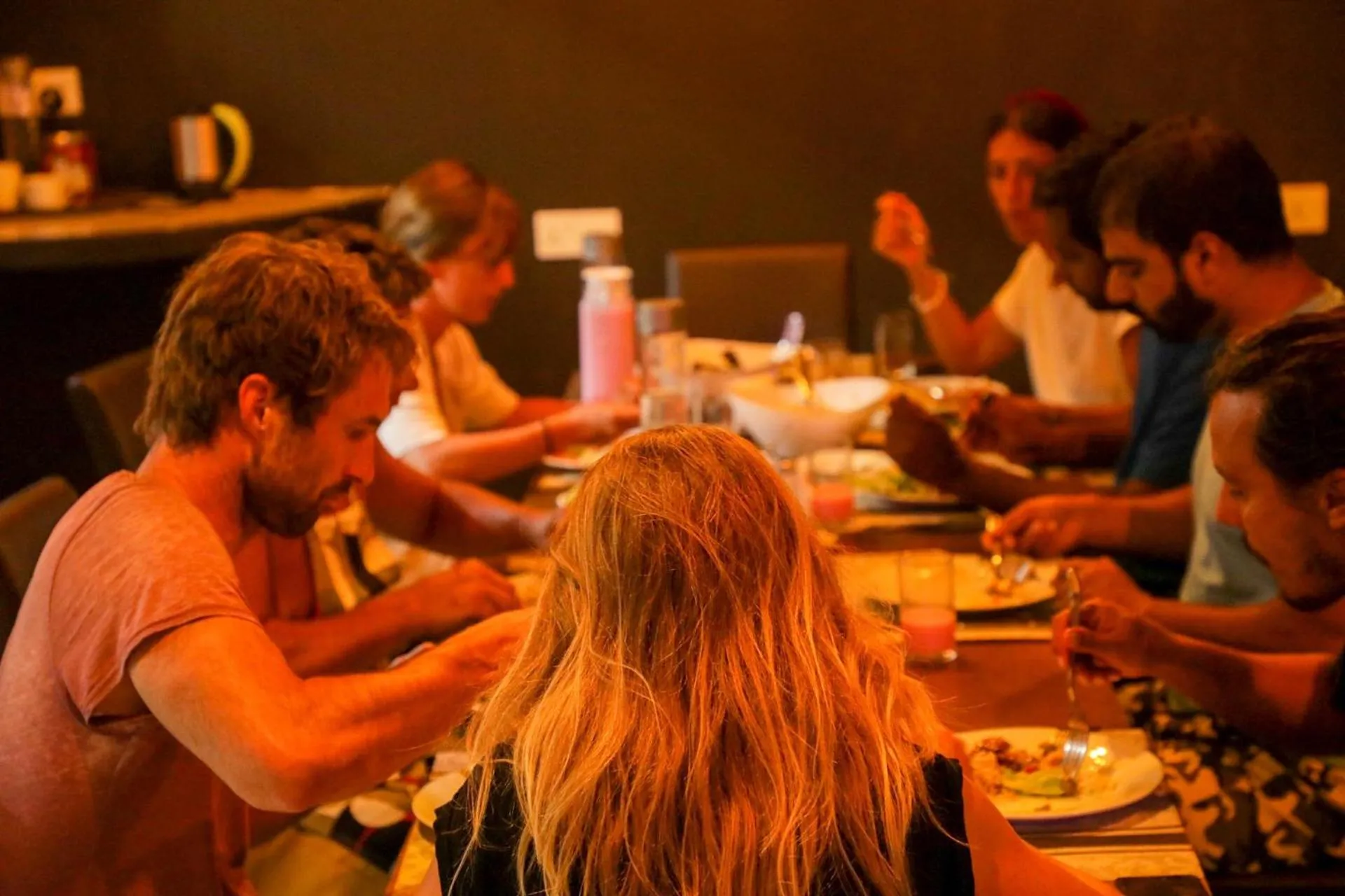 Des convives sont attablés et partagent un repas dans une ambiance chaleureuse.