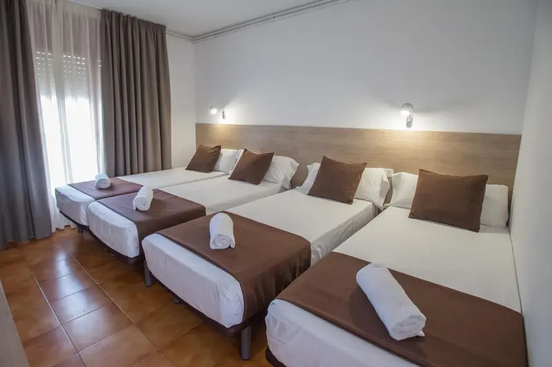 Une chambre avec plusieurs lits simples et des oreillers.