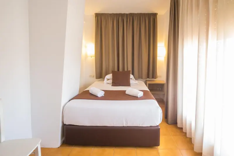 Une chambre lumineuse avec un lit recouvert d'une courtepointe et de coussins.
