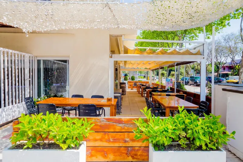 Terrasse ombragée avec tables et chaises en bois.