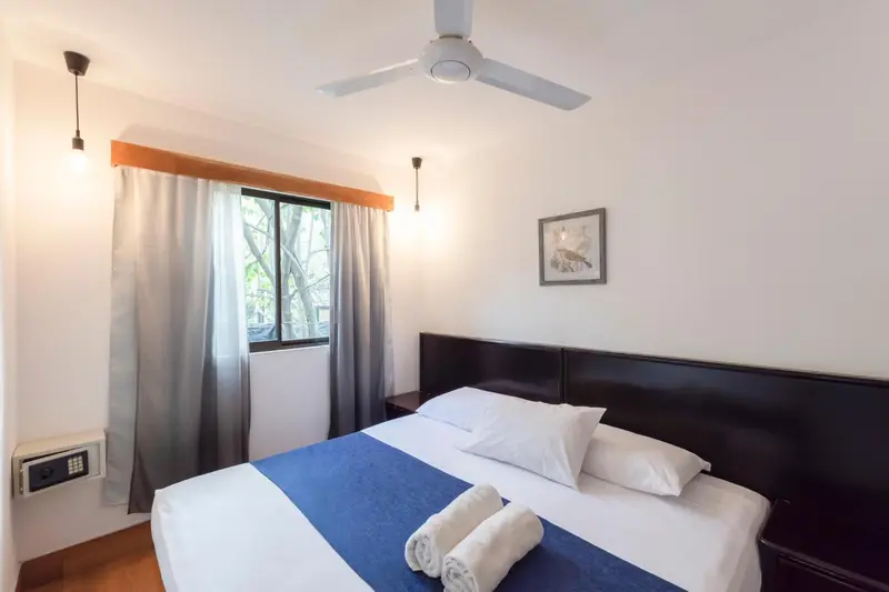 Une chambre lumineuse avec un lit recouvert d'une couverture bleue et de deux oreillers.
