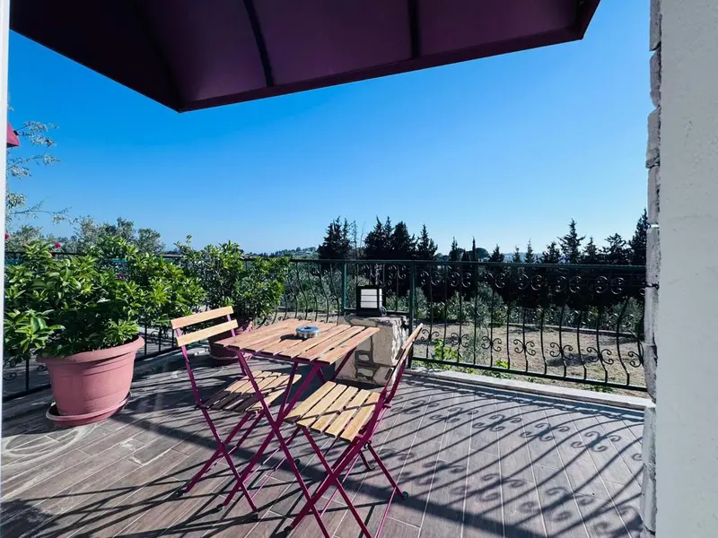 Une table et des chaises en bois sur une terrasse carrelée avec une vue sur la végétation.