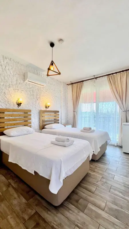 Chambre lumineuse avec deux lits simples et une fenêtre.