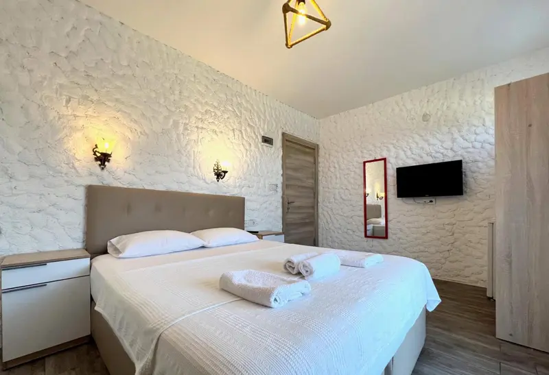 Une chambre lumineuse avec un grand lit et un mur texturé.