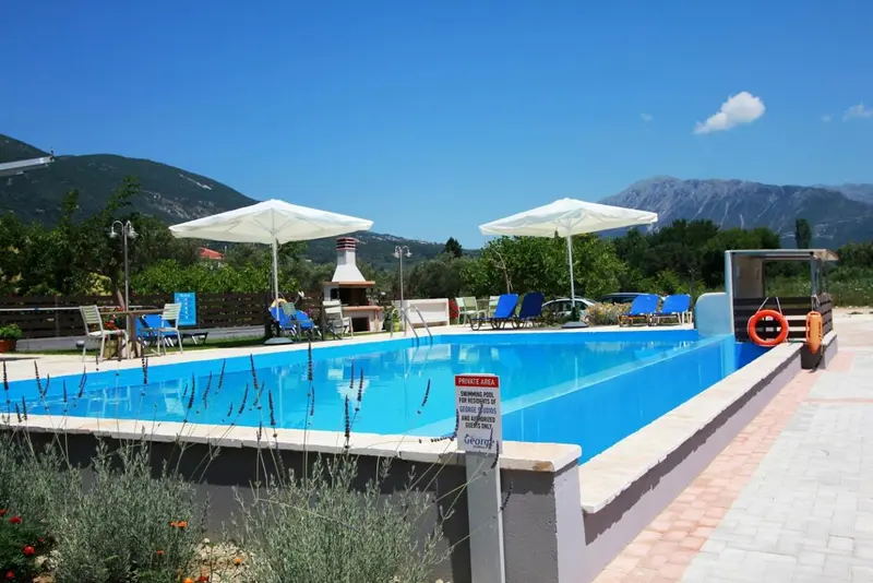 Une piscine rectangulaire avec des transats et des parasols, entourée d'une terrasse ensoleillée.