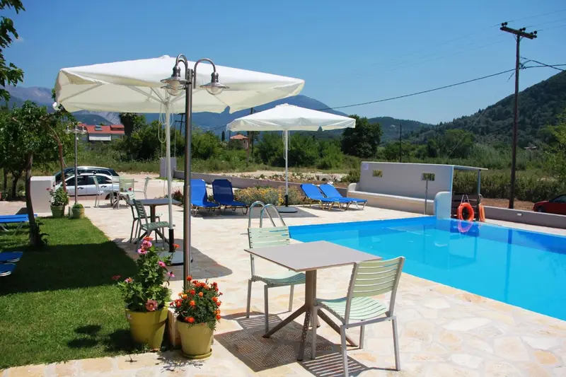 Terrasse avec tables et chaises près d'une piscine ensoleillée.