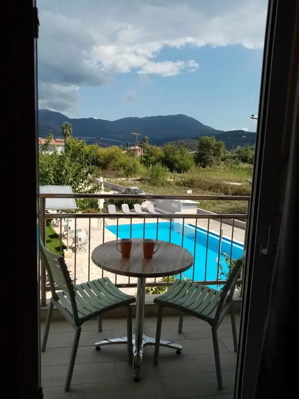 Une table ronde avec deux tasses sur une terrasse ensoleillée surplombe une piscine.