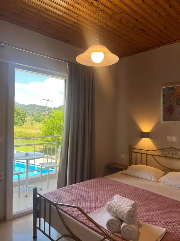 Une chambre lumineuse avec un lit et un accès à une terrasse avec vue sur une piscine.