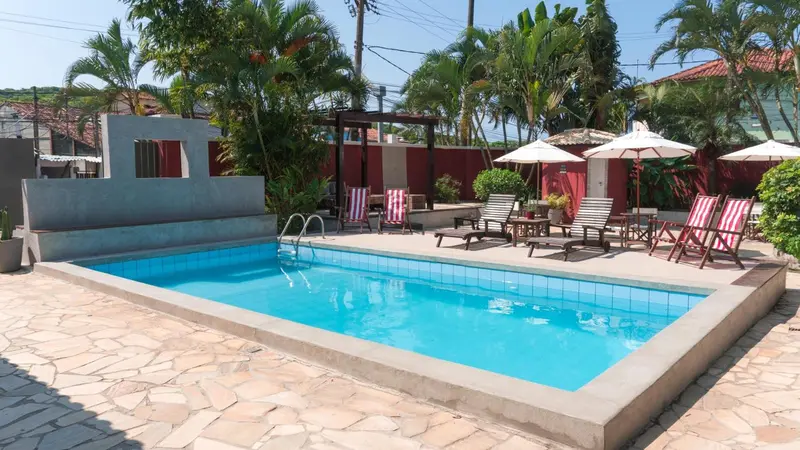 Piscine rectangulaire entourée d'un sol pavé et de végétation tropicale.