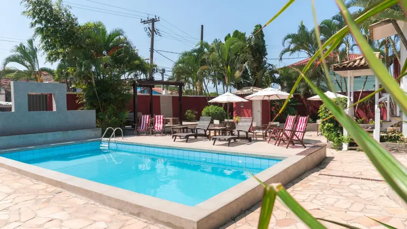 Une piscine rectangulaire bordée d'une terrasse pavée avec des transats et des parasols.