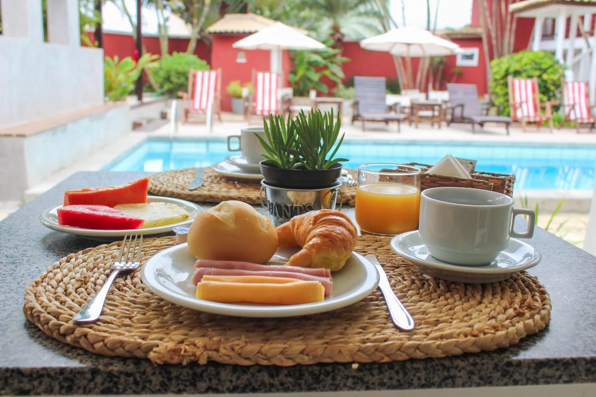Une table est dressée avec un petit-déjeuner copieux au bord d'une piscine.