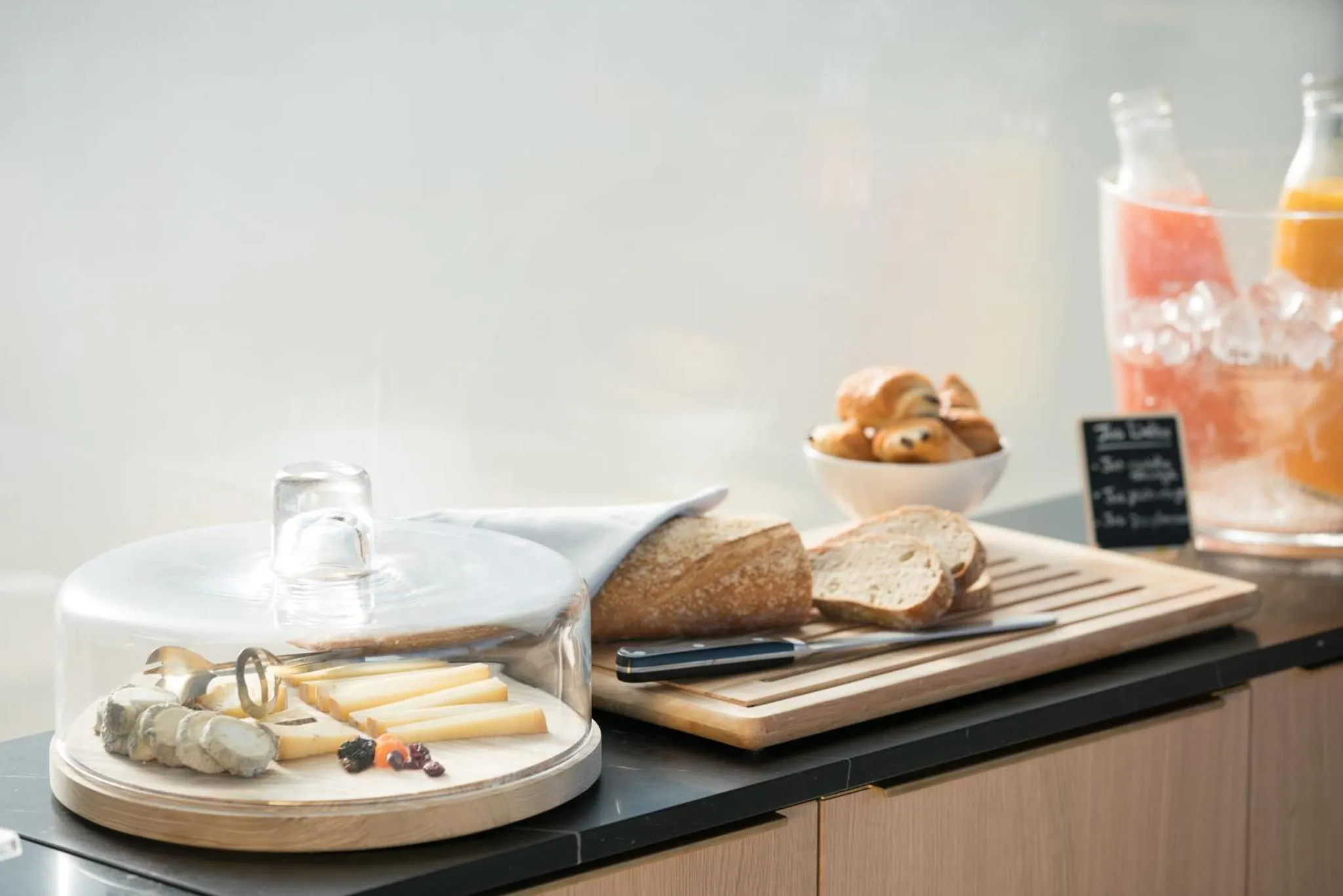 Assortiment de viennoiseries, fromages et boissons fraîches présentés sur un buffet.