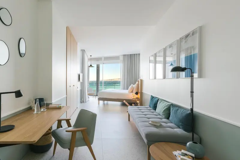 Une chambre lumineuse avec un canapé et un bureau donnant sur une vue dégagée.