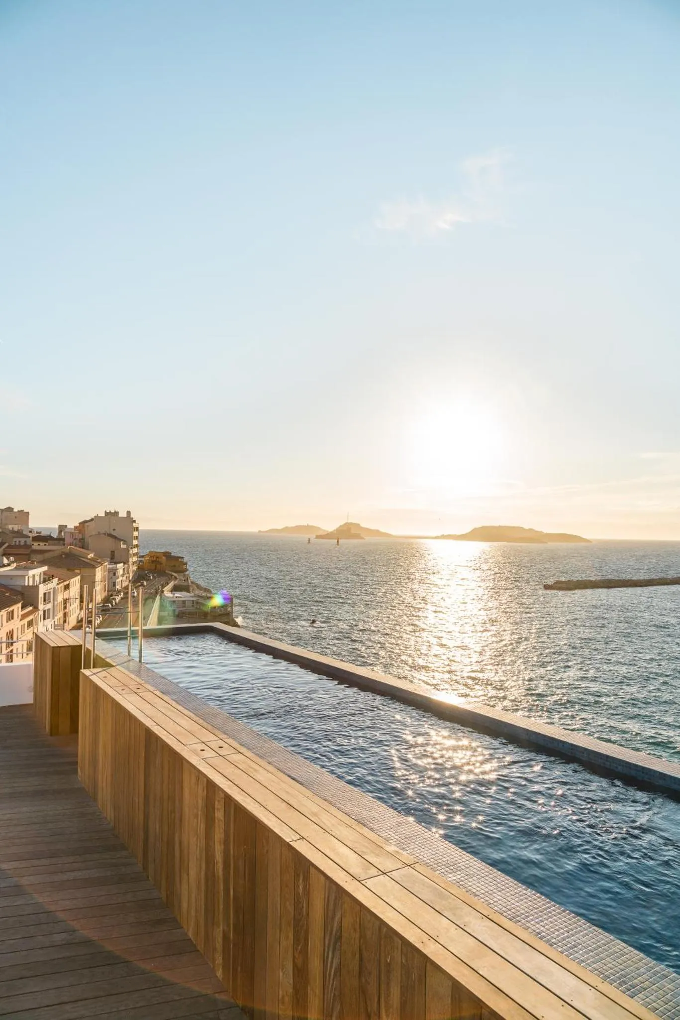 Une piscine à débordement offre une vue sur la mer et le soleil couchant.