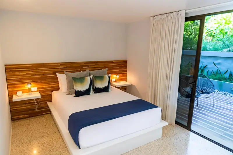 Une chambre lumineuse avec un grand lit et un accès à une terrasse.