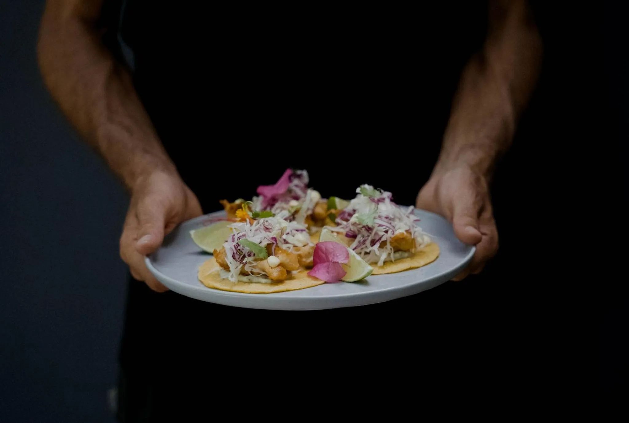 Une personne présente une assiette de tacos décorés.