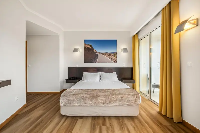 Une chambre lumineuse avec un grand lit et un tableau mural.