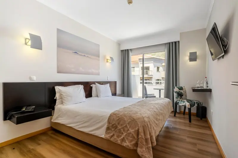 Une chambre lumineuse avec un grand lit et un accès à un balcon.