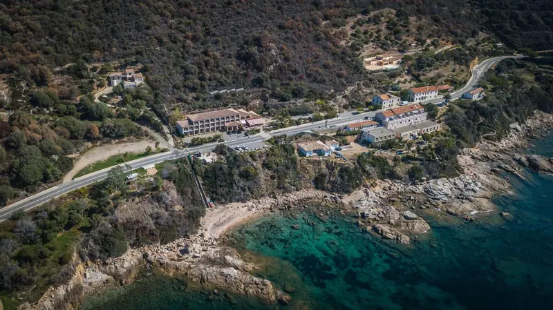 Vue aérienne d'un ensemble immobilier au bord de la mer et d'une route côtière.