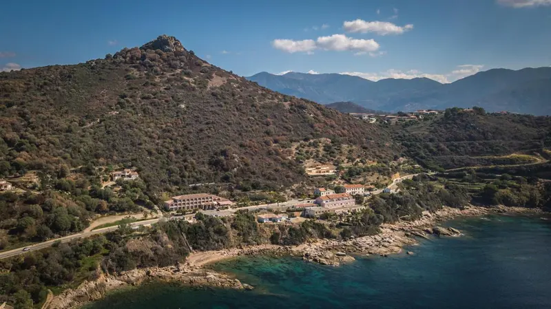 Vue aérienne d'un établissement au bord de la mer, adossé à une montagne.