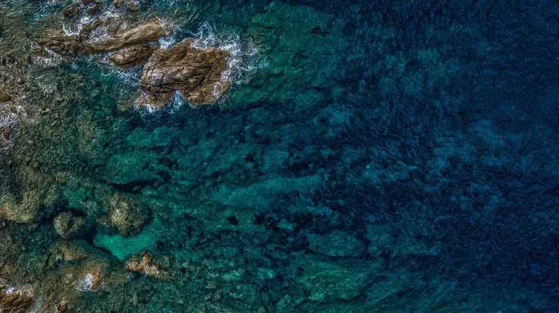 Vue aérienne d'une côte rocheuse et de l'eau turquoise.