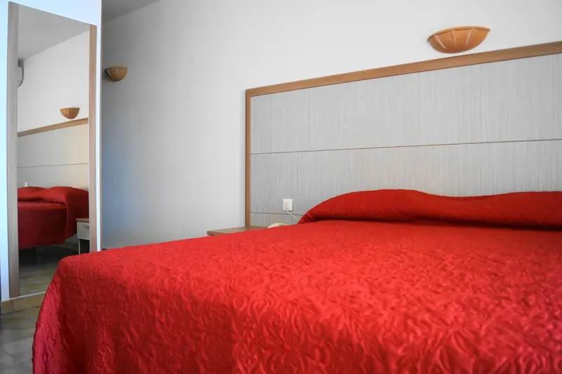 Une chambre à coucher avec un lit rouge et un miroir.