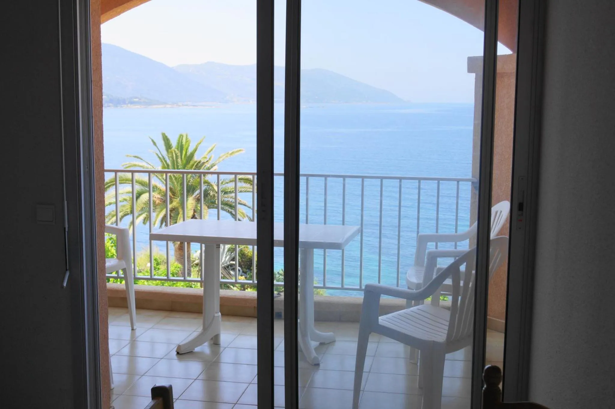Vue sur la mer depuis une terrasse avec mobilier blanc.
