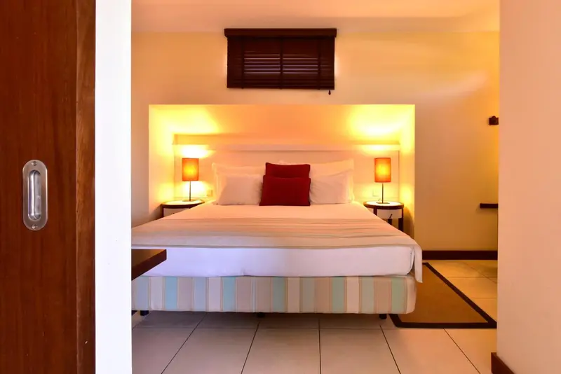 Une chambre lumineuse avec un grand lit recouvert d'une courtepointe colorée.