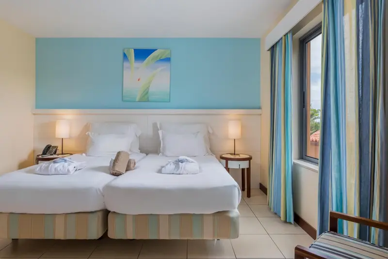 Une chambre lumineuse avec deux lits simples et une décoration sobre.