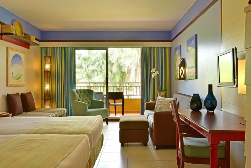 Une chambre lumineuse avec un coin salon et vue sur la végétation.