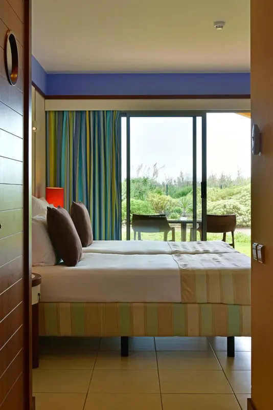 Chambre lumineuse avec un lit double donnant sur une terrasse et un jardin.