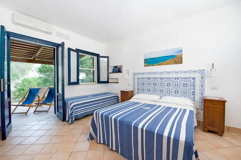 Chambre lumineuse avec un lit et un accès à une terrasse.
