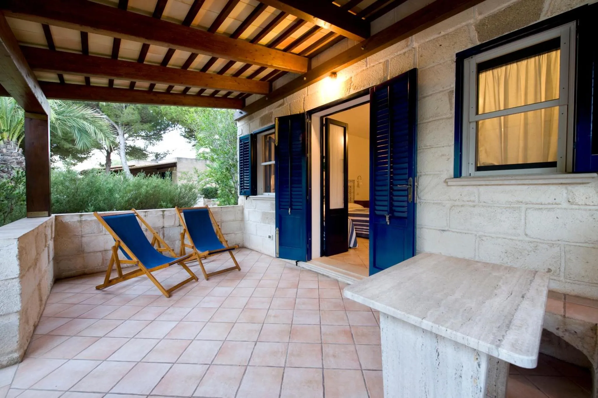 Terrasse ombragée avec deux transats et une table basse.