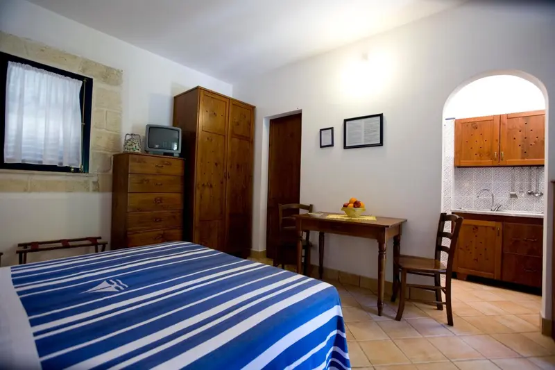 Une chambre avec un lit recouvert d'une couverture rayée et une petite table à manger.