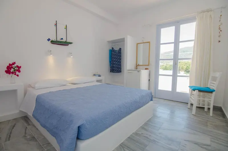 Une chambre lumineuse avec un lit fait et une vue sur l'extérieur.