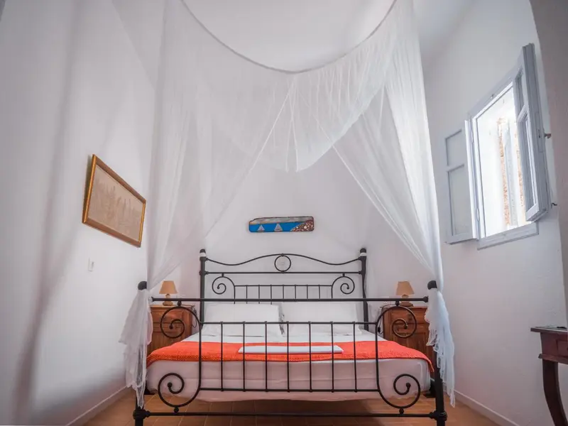 Une chambre lumineuse avec un lit à baldaquin et une décoration sobre.