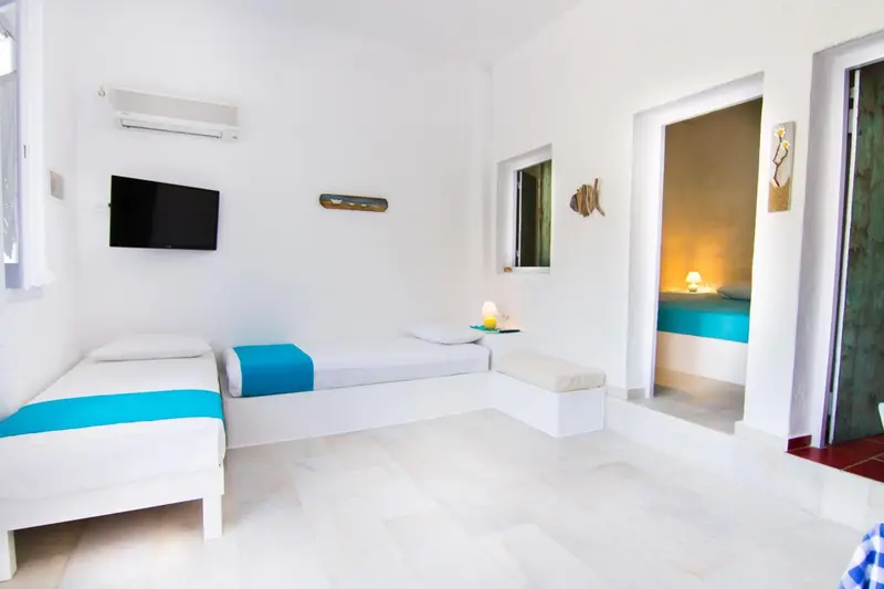 Une chambre lumineuse avec deux lits simples et un accès vers une salle de bain.